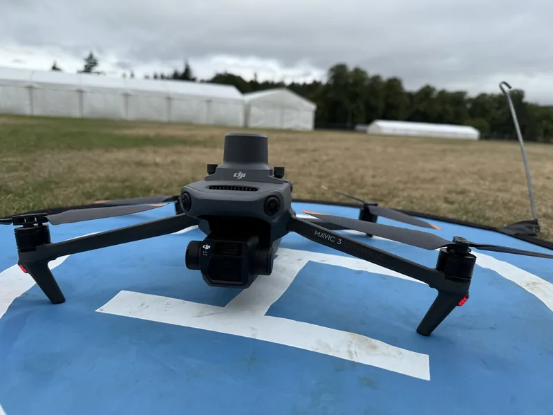 A DJI drone on its landing pad in a field, ready to fly